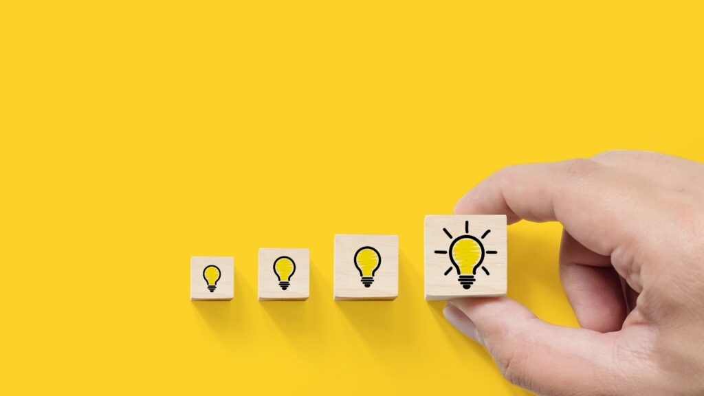 電球の絵のついた木のブロックと手