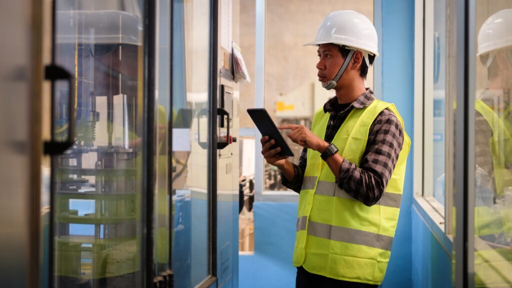 工場でタブレット端末を見ながら作業する人