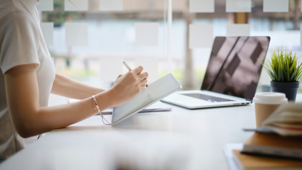 女性がパソコンとタブレットで仕事をしている