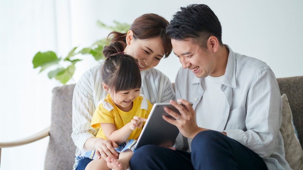 笑顔でタブレットを操作する子供と笑顔の両親
