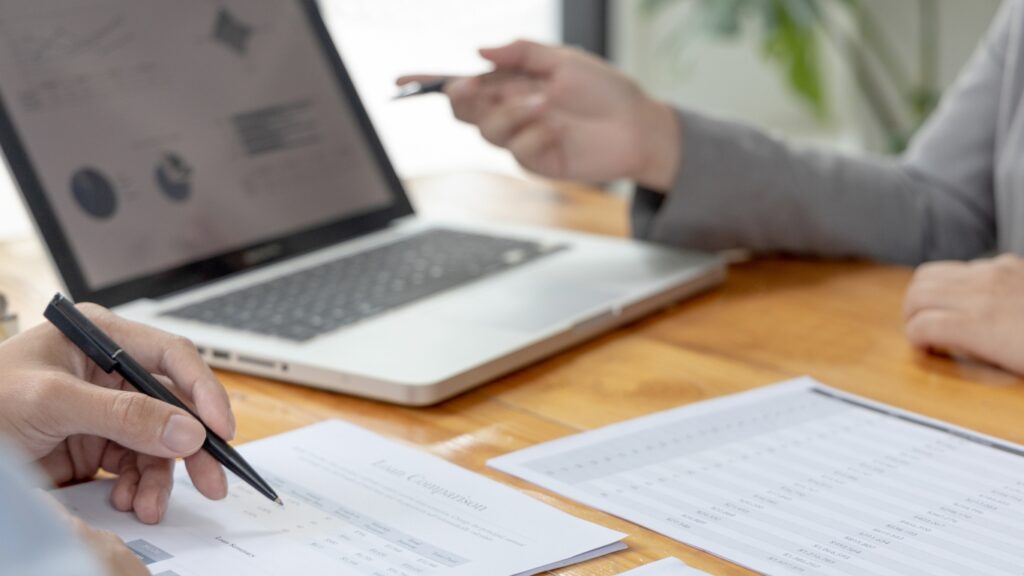 ノートパソコンを使って説明するビジネスパーソン