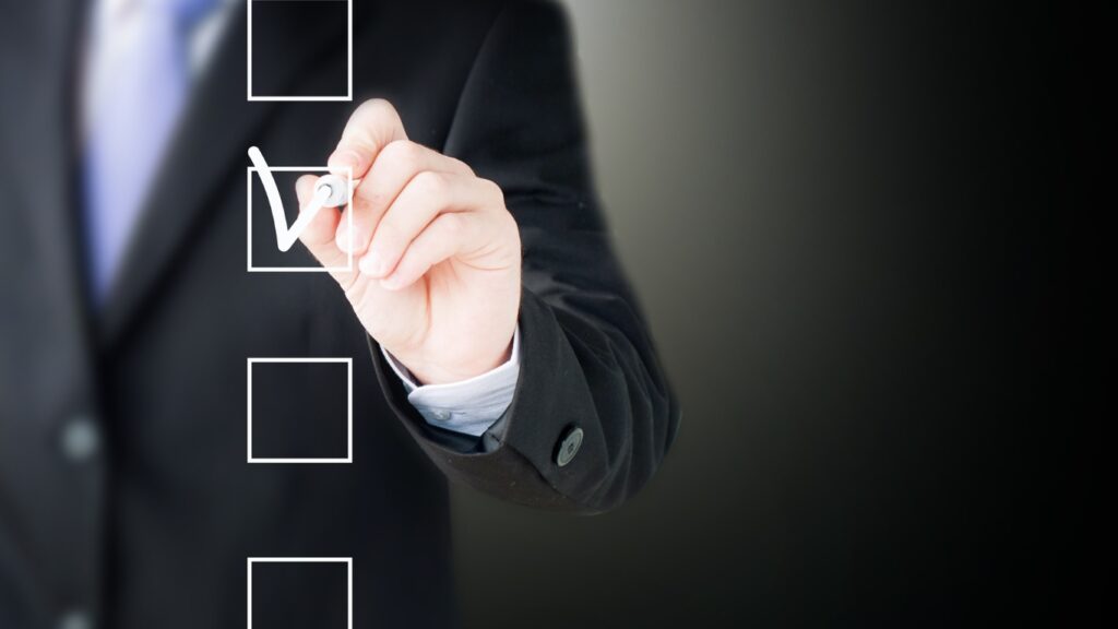 チェックリストにチェックを入れるビジネスパーソン