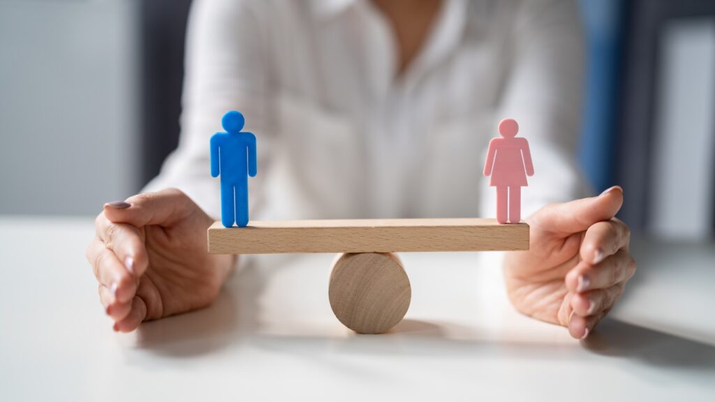 男女のフィギュアがシーソーに乗っている