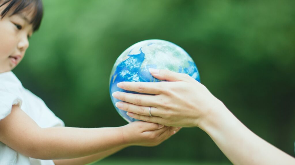 子どもと大人、地球儀を一緒に持っている