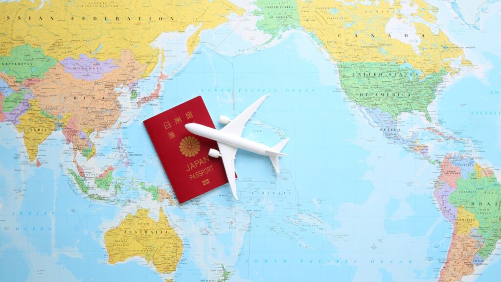 世界地図の上に日本のパスポートと飛行機