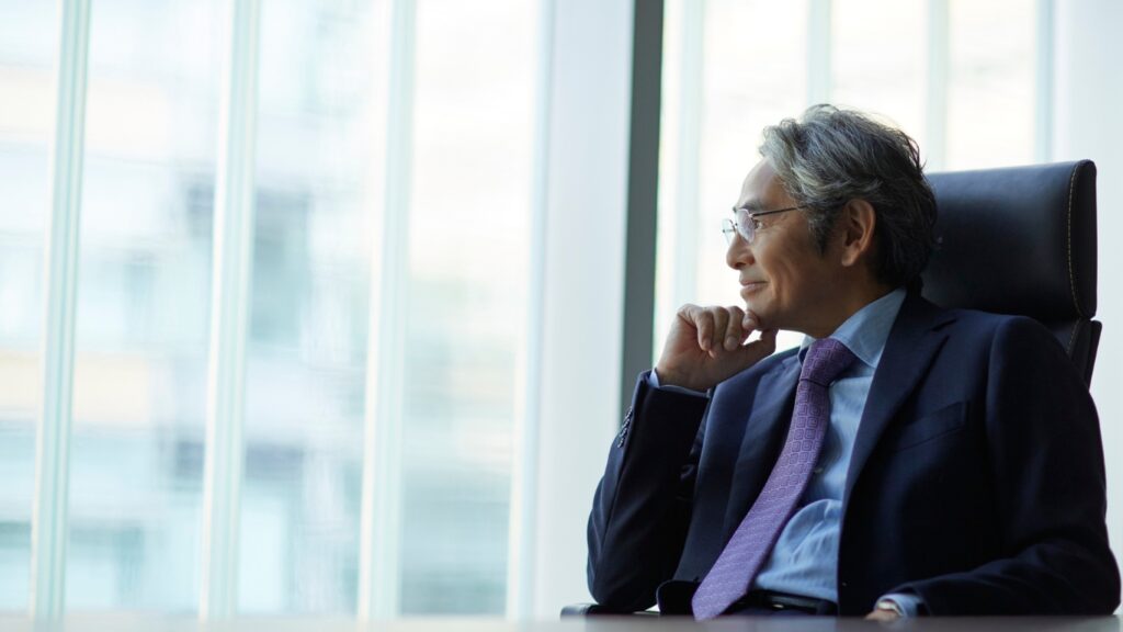 経営者が窓辺に座り考えている