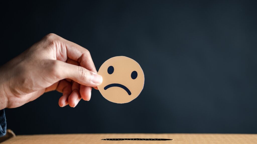 不満の顔の紙を持つ手